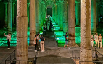 Tourists exploring the illuminated Basilica Cistern in Istanbul during an Old City Walking tour.