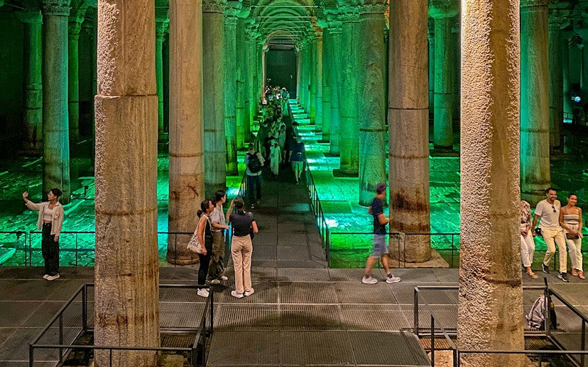 Tourists exploring the illuminated Basilica Cistern in Istanbul during an Old City Walking tour.
