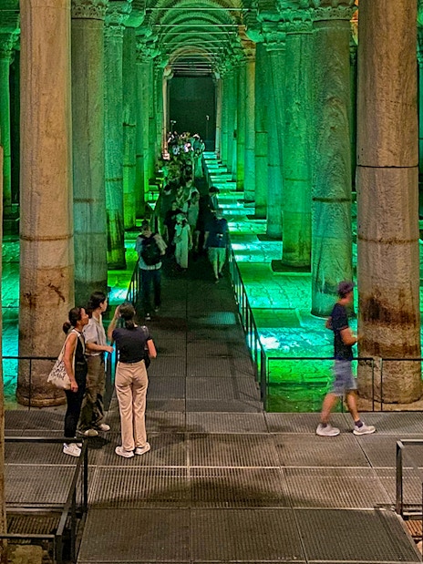 Tourists exploring the illuminated Basilica Cistern in Istanbul during an Old City Walking tour.