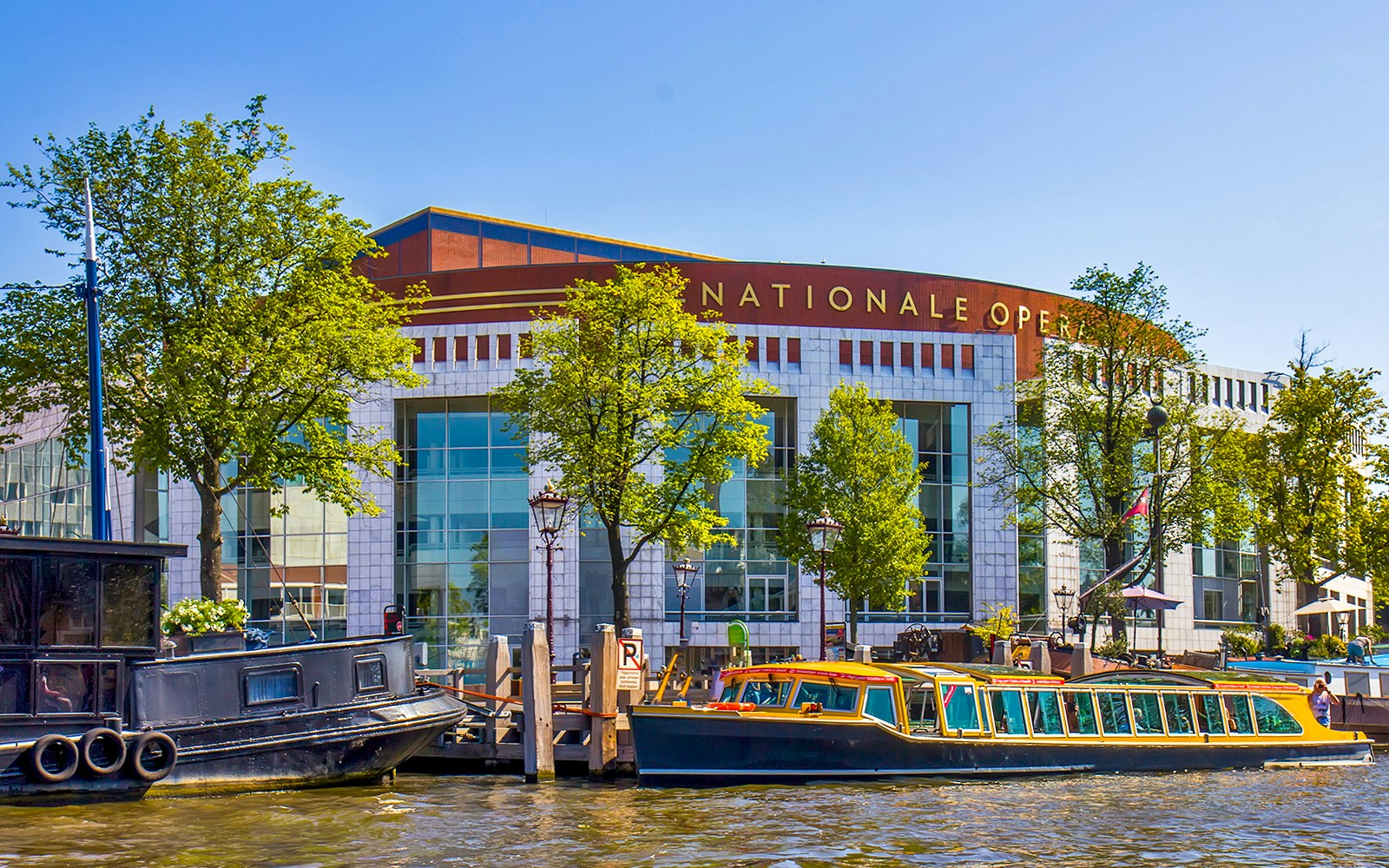 Dutch National Opera building with canal boats in Amsterdam.