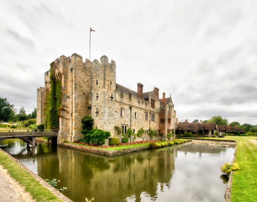 Hever Castle in Kent, England, surrounded by lush gardens and a tranquil moat.