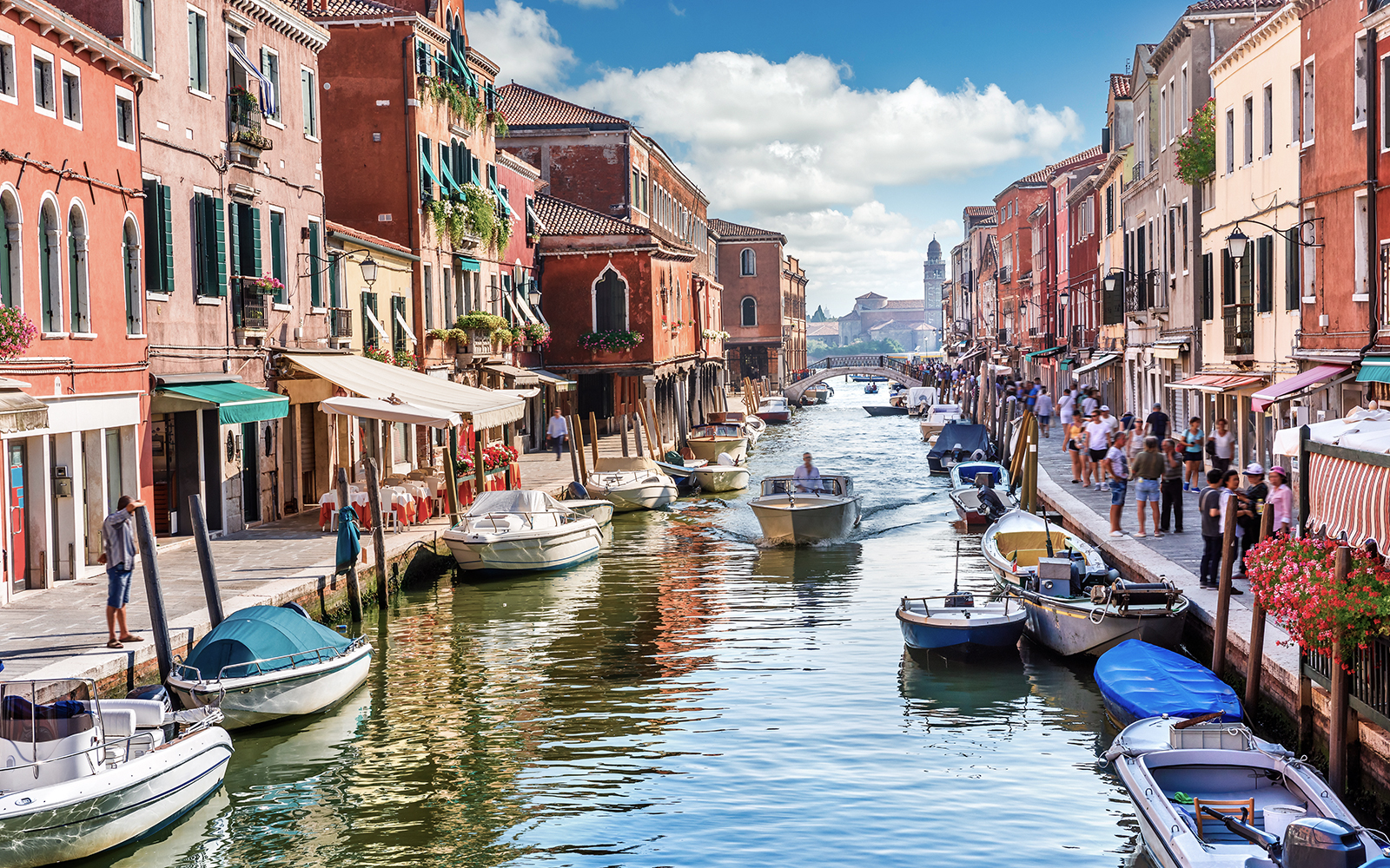 Venice canal with boats and colorful buildings, part of Venice City Pass attractions.