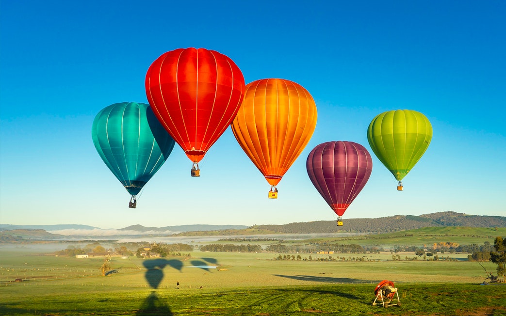 Hot air balloons floating over Yarra Valley at sunrise.