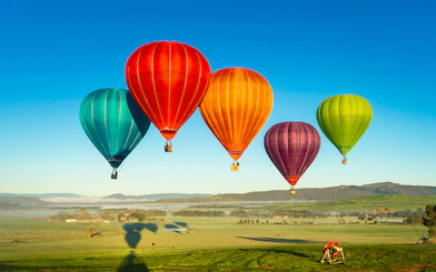 Hot air balloons floating over Yarra Valley at sunrise.