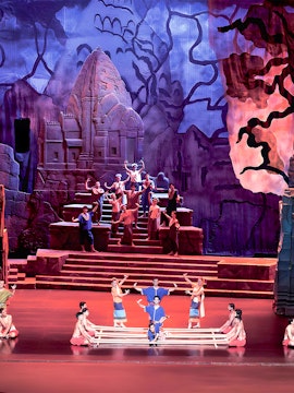 Siam Niramit Phuket performers in traditional attire on stage with ancient temple backdrop.