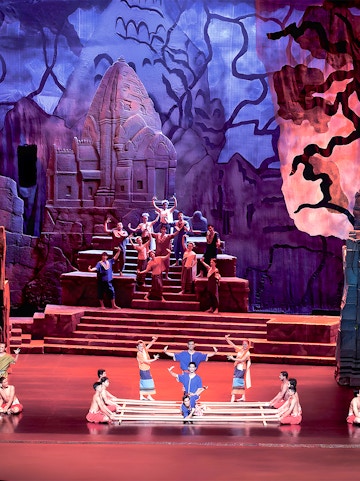 Siam Niramit Phuket performers in traditional attire on stage with ancient temple backdrop.