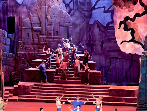 Siam Niramit Phuket performers in traditional attire on stage with ancient temple backdrop.