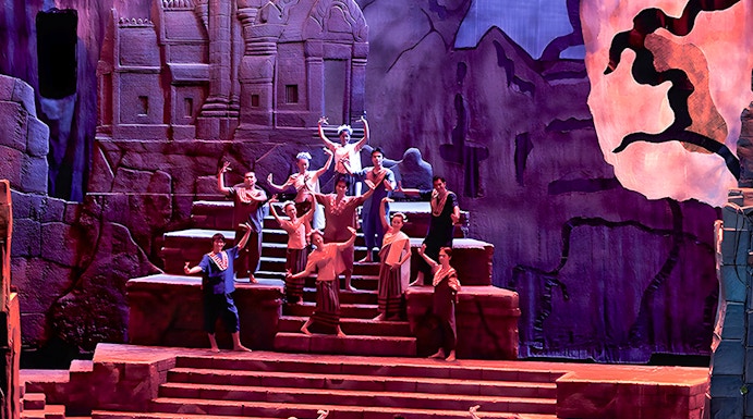 Siam Niramit Phuket performers in traditional attire on stage with ancient temple backdrop.