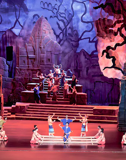 Siam Niramit Phuket performers in traditional attire on stage with ancient temple backdrop.