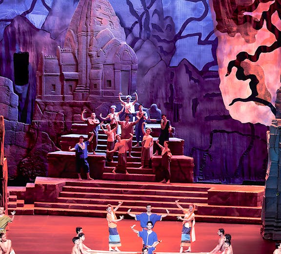 Siam Niramit Phuket performers in traditional attire on stage with ancient temple backdrop.