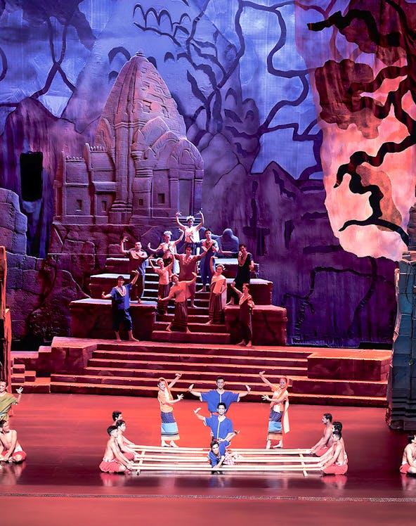 Siam Niramit Phuket performers in traditional attire on stage with ancient temple backdrop.
