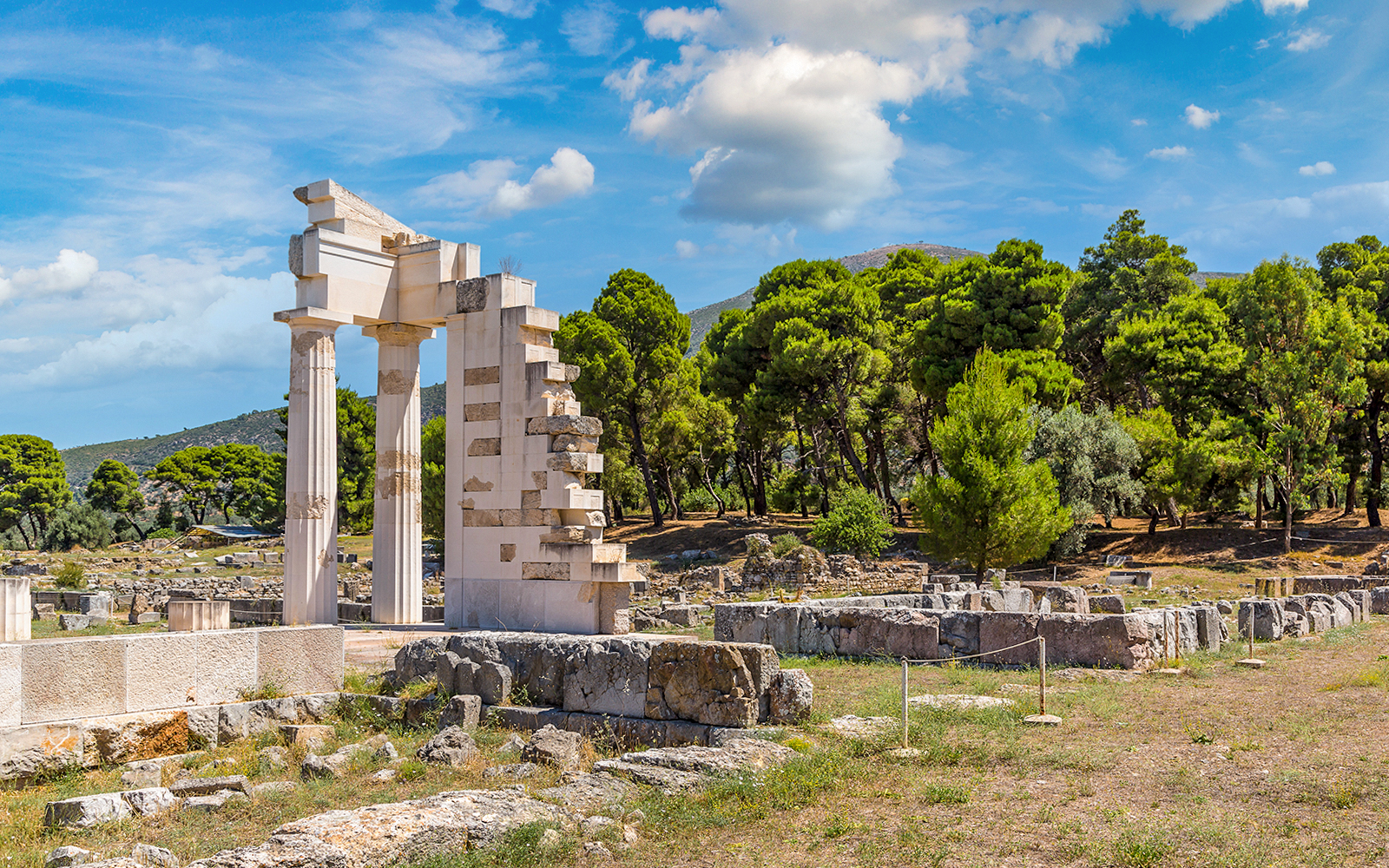 Epidaurus Ancient Theatre ruins with surrounding greenery and blue sky.
