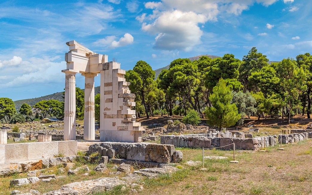 Epidaurus Ancient Theatre ruins with surrounding greenery and blue sky.