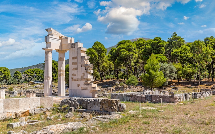 Epidaurus Ancient Theatre ruins with surrounding greenery and blue sky.