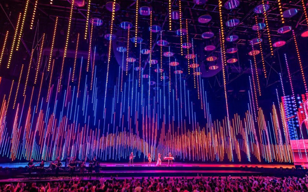 ABBA Voyage concert stage with colorful light display and audience.