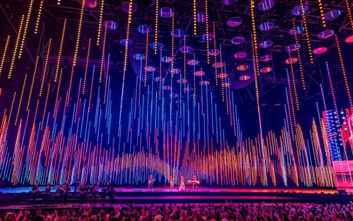 ABBA Voyage concert stage with colorful light display and audience.