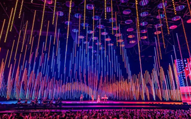ABBA Voyage concert stage with colorful light display and audience.