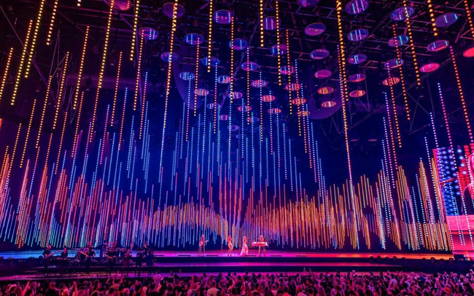 ABBA Voyage concert stage with colorful light display and audience.