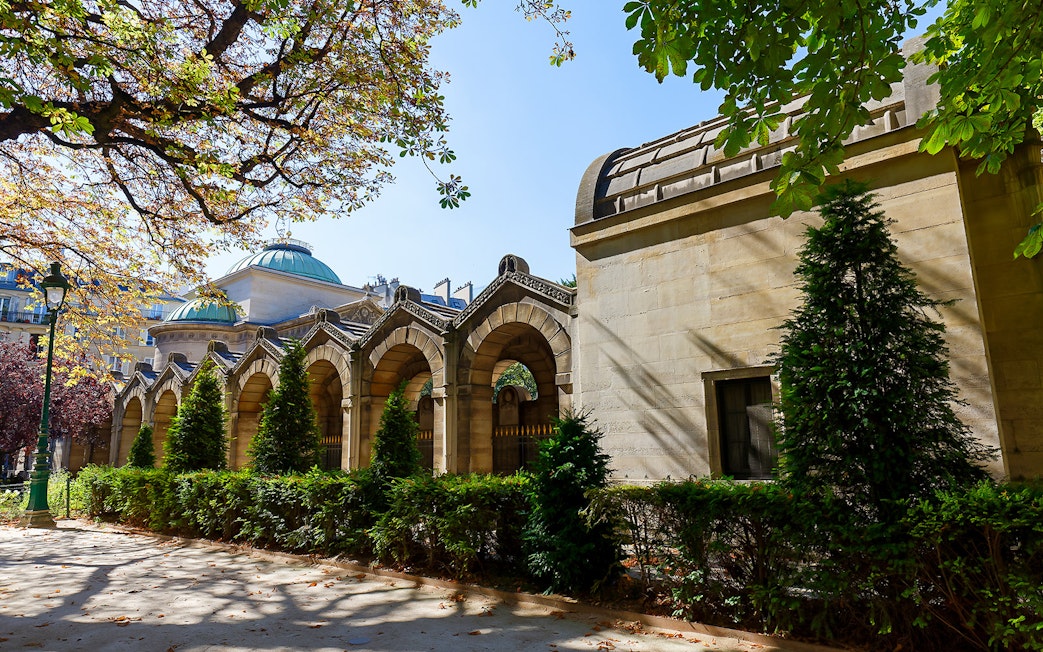 Expiatory Chapel exterior with arches and greenery in Paris, France.