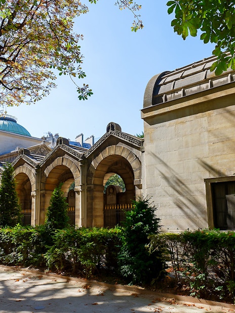 Expiatory Chapel exterior with arches and greenery in Paris, France.