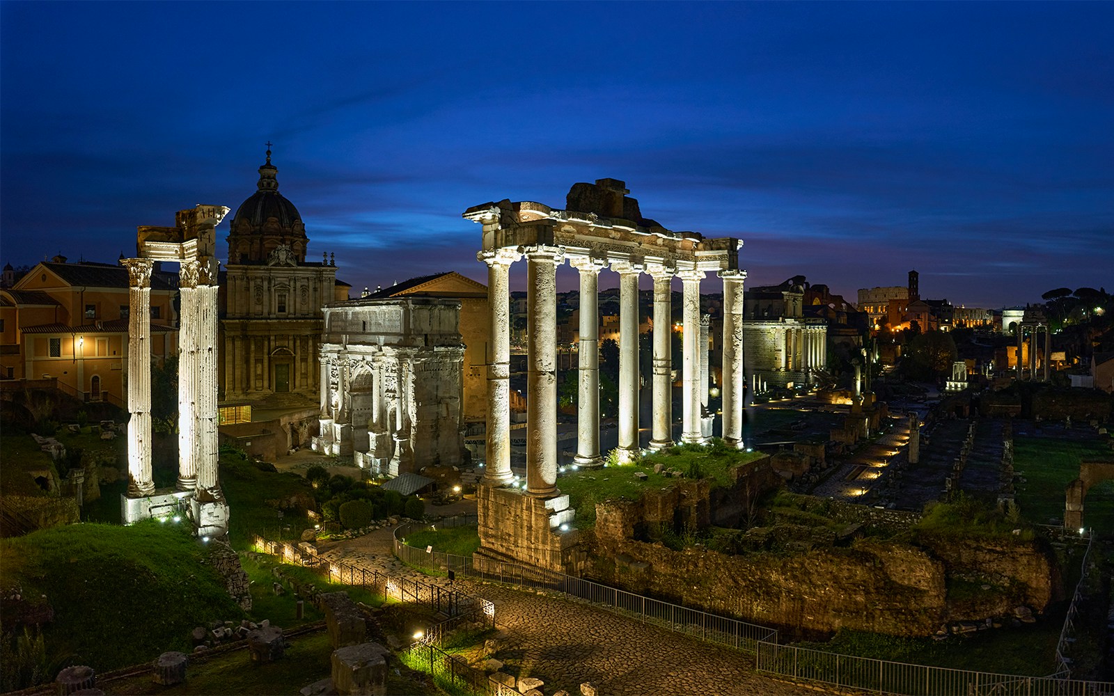 Roman Forum illuminated at night with ancient columns and ruins in Rome, Italy.