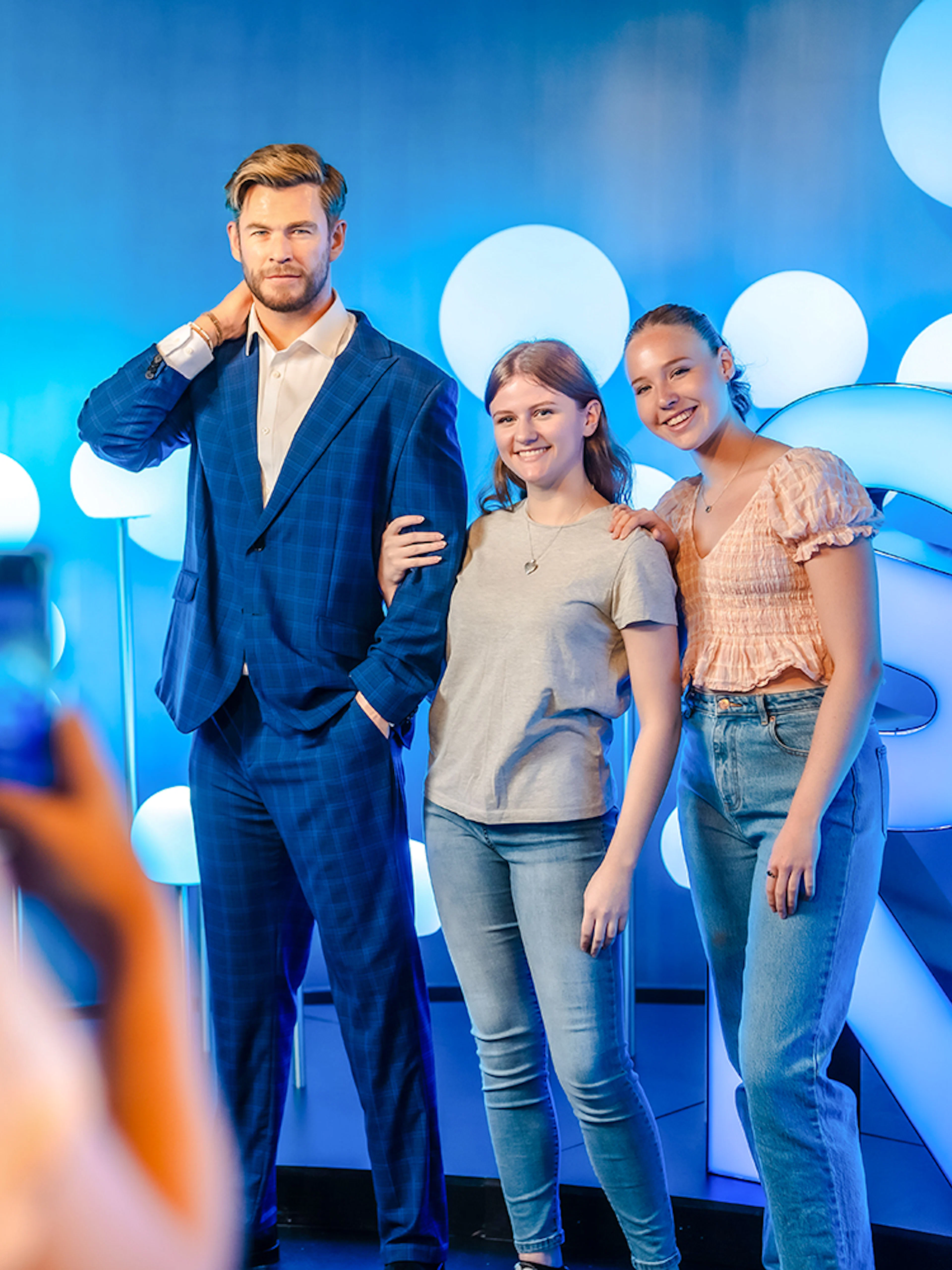 Visitors posing with Chris Hemsworth wax figure at Madame Tussauds.