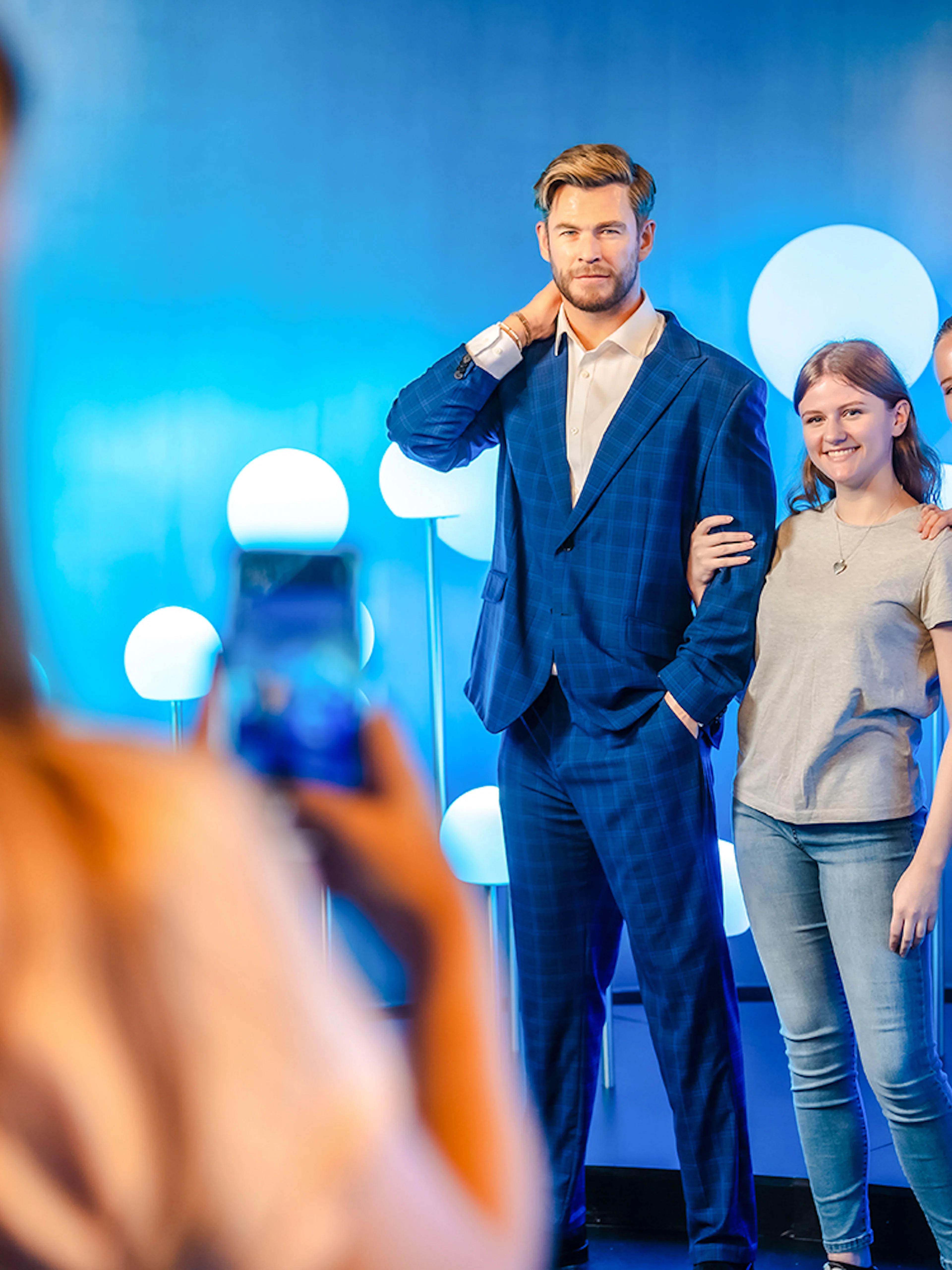 Visitors posing with Chris Hemsworth wax figure at Madame Tussauds.