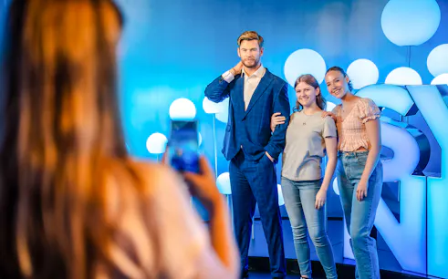 Visitors posing with Chris Hemsworth wax figure at Madame Tussauds.
