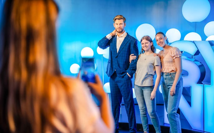 Visitors posing with Chris Hemsworth wax figure at Madame Tussauds.