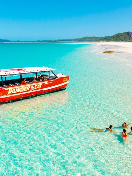 Thundercat boat near Whitsundays beach with people swimming in clear water.