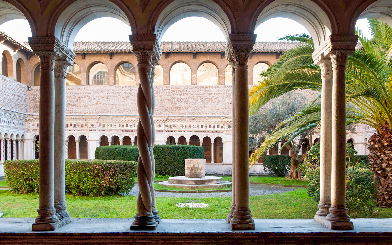 Cloister view at St. John Lateran Basilica, Rome, with arches and garden.