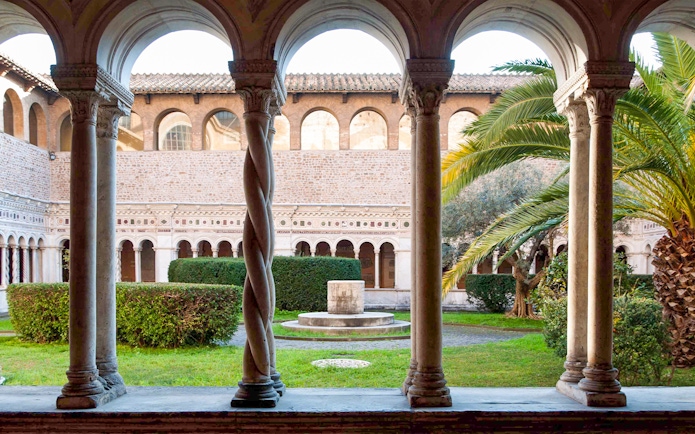 Cloister view at St. John Lateran Basilica, Rome, with arches and garden.