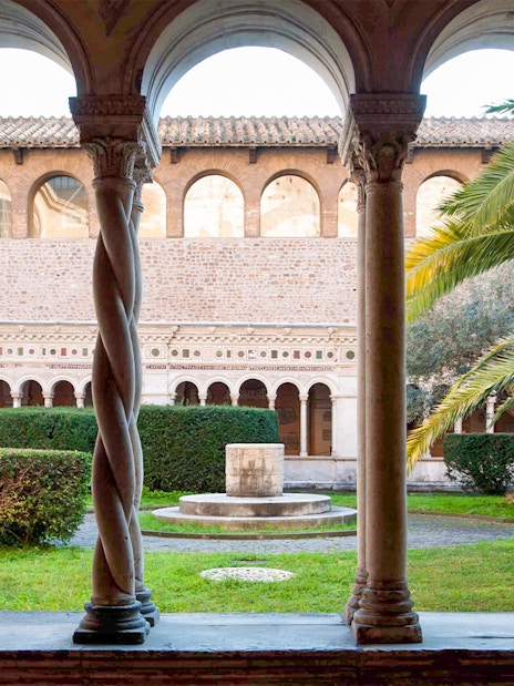 Cloister view at St. John Lateran Basilica, Rome, with arches and garden.