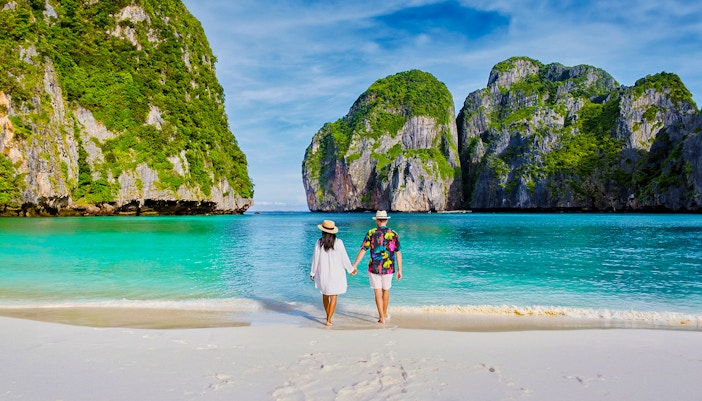 Couple standing in Phi Phi Island, admiring limestone and nature, Thailand.