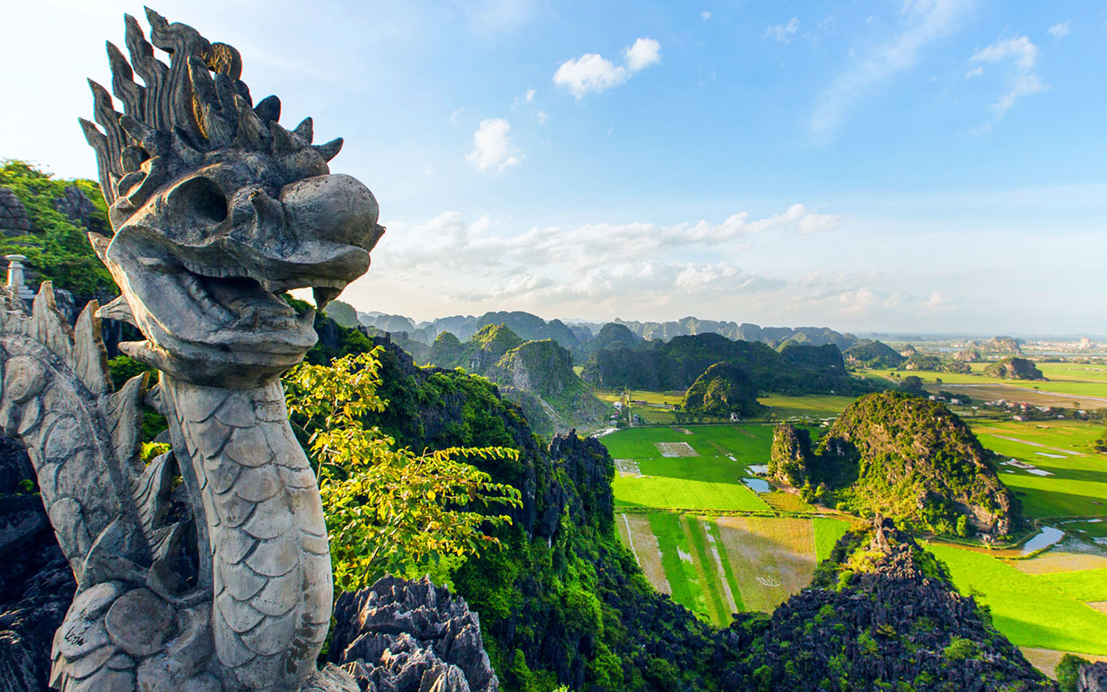 Panoramic view from Mua Caves viewpoint, Ninh Bình, Vietnam, with stone dragon sculpture in foreground.
