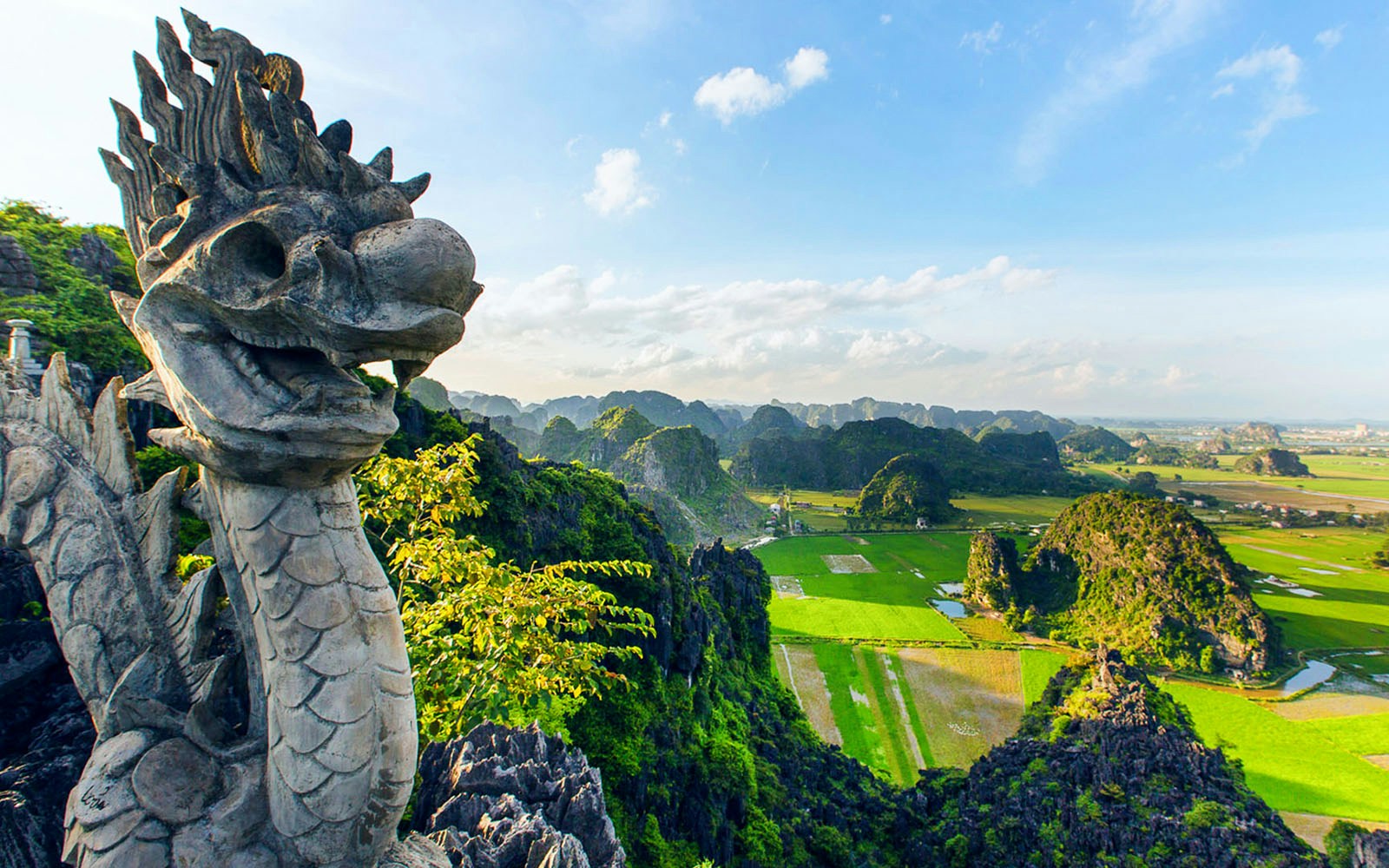 Panoramic view from Mua Caves viewpoint, Ninh Bình, Vietnam, with stone dragon sculpture in foreground.