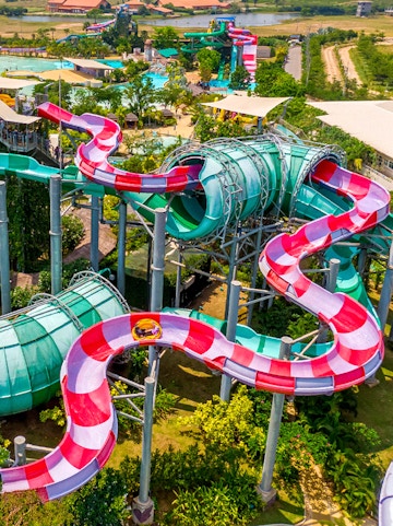 Colorful water slide at Ramayana Water Park, Thailand, with lush greenery and pools in the background.