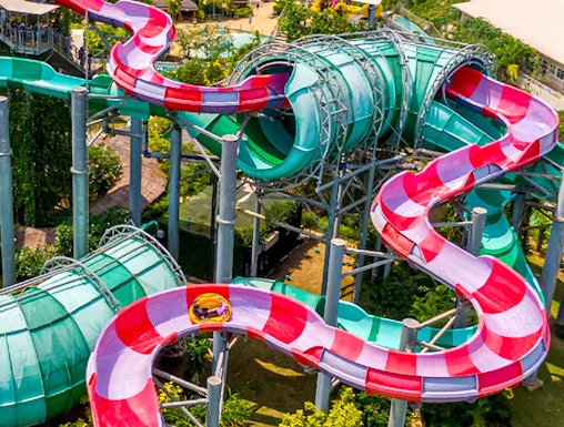 Colorful water slide at Ramayana Water Park, Thailand, with lush greenery and pools in the background.