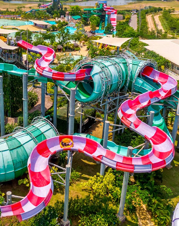 Colorful water slide at Ramayana Water Park, Thailand, with lush greenery and pools in the background.