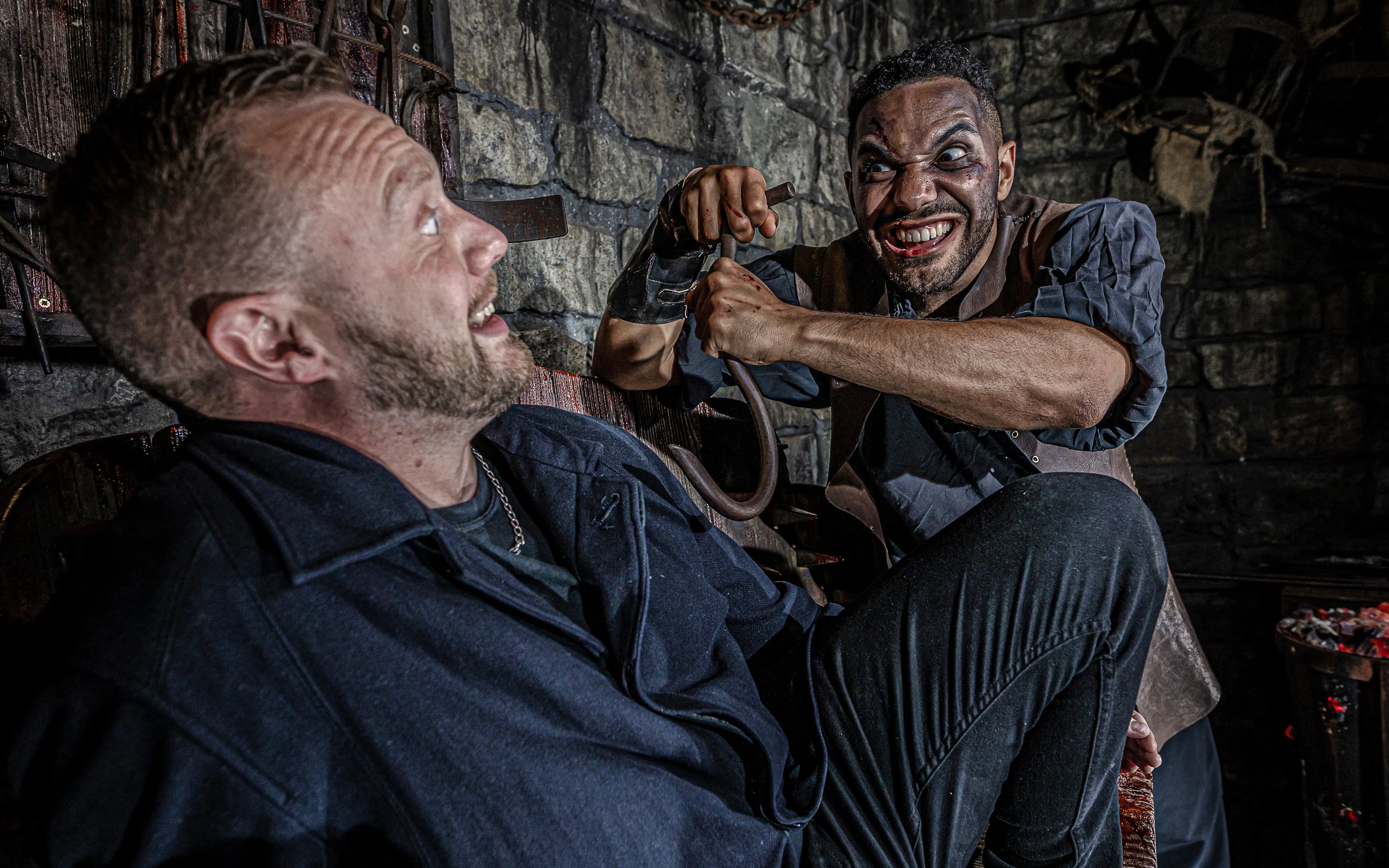 Man in costume menacing another man in the Torture Chamber at the York Dungeon.