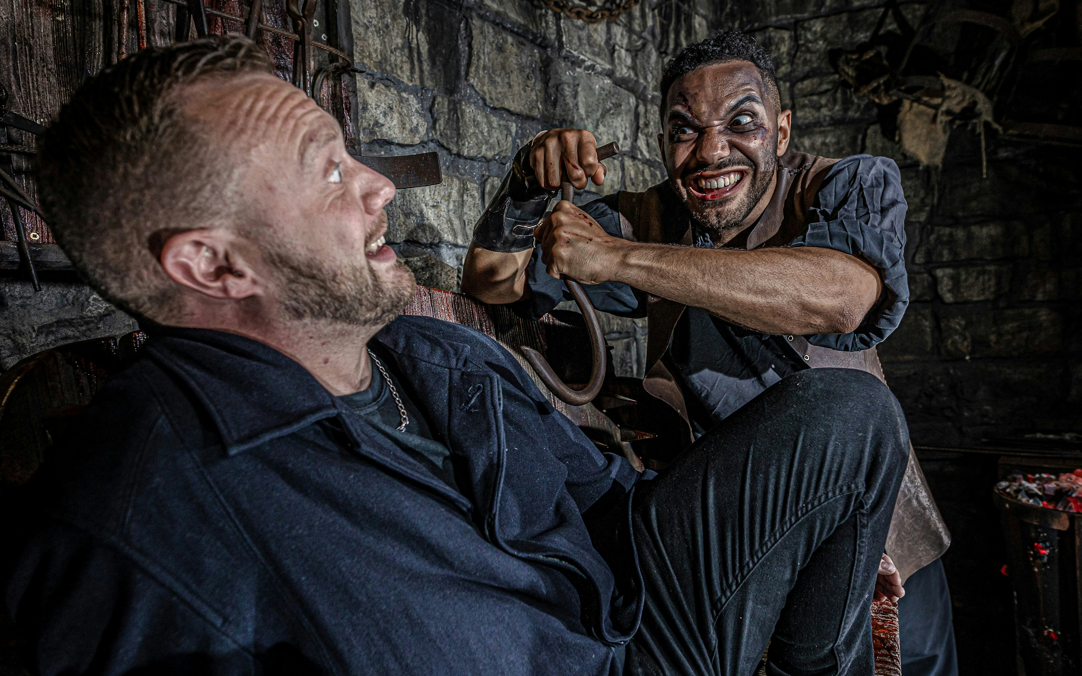 Man in costume menacing another man in the Torture Chamber at the York Dungeon.