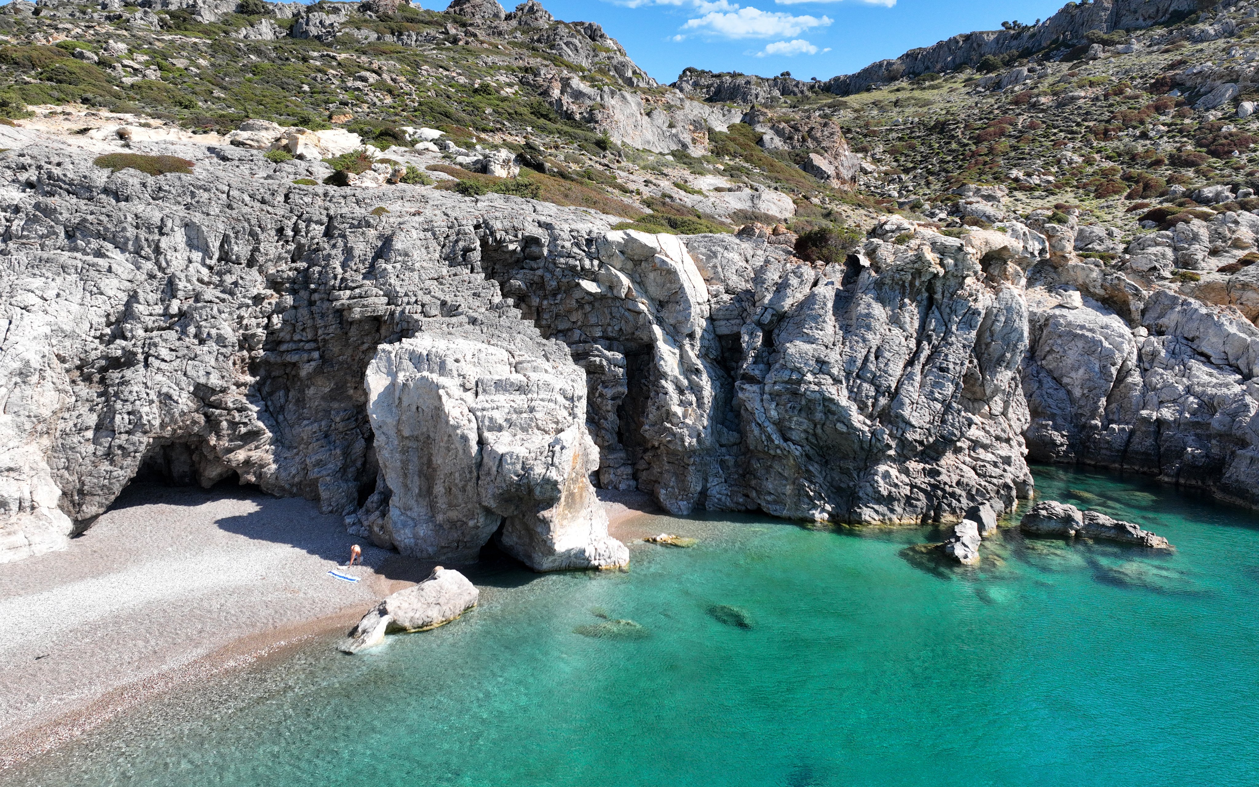 Traganou Caves with rocky cliffs and turquoise water, Rhodes, Greece.