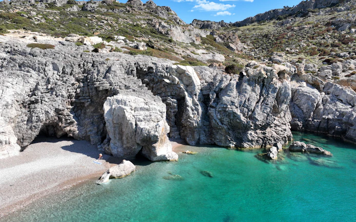 Traganou Caves with rocky cliffs and turquoise water, Rhodes, Greece.