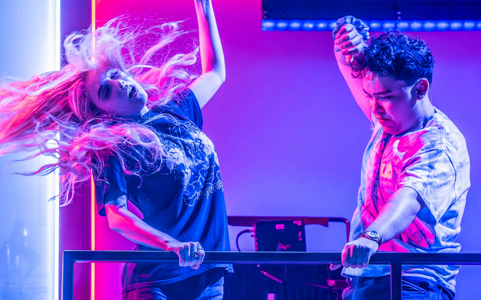 Performers dancing energetically under vibrant lights in a scene from Next to Normal.