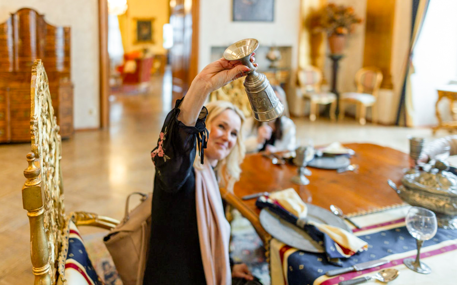 Guest raising a medieval-style goblet during dinner at Dětenice Castle near Prague.
