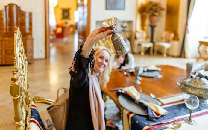 Guest raising a medieval-style goblet during dinner at Dětenice Castle near Prague.