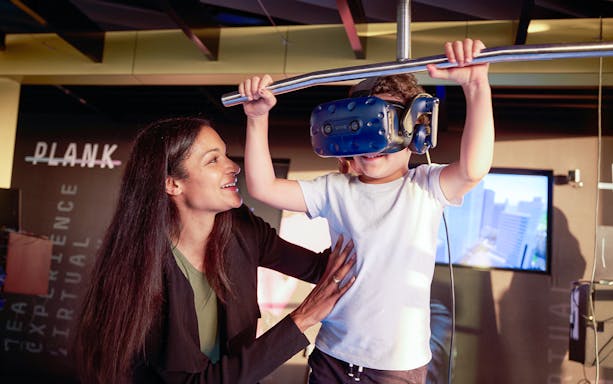 Child experiencing virtual reality at Melbourne Skydeck with VR headset, guided by an adult.