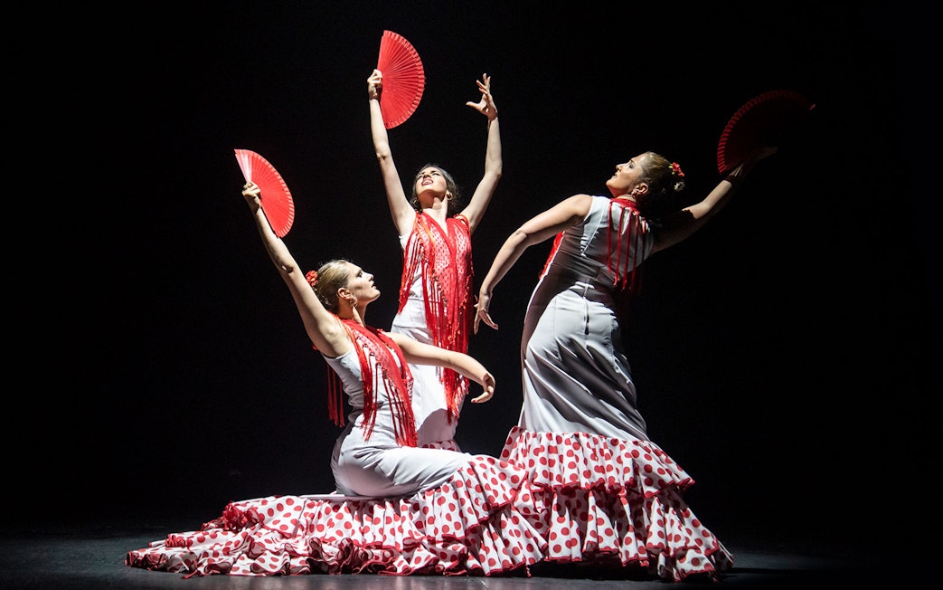 Flamenco dancers with red fans performing at Teatro Flamenco Barcelona.