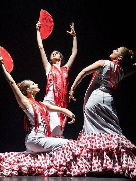 Flamenco dancers with red fans performing at Teatro Flamenco Barcelona.