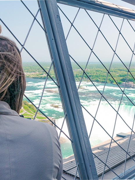 Woman viewing Niagara Falls from Skylon Tower observatory.